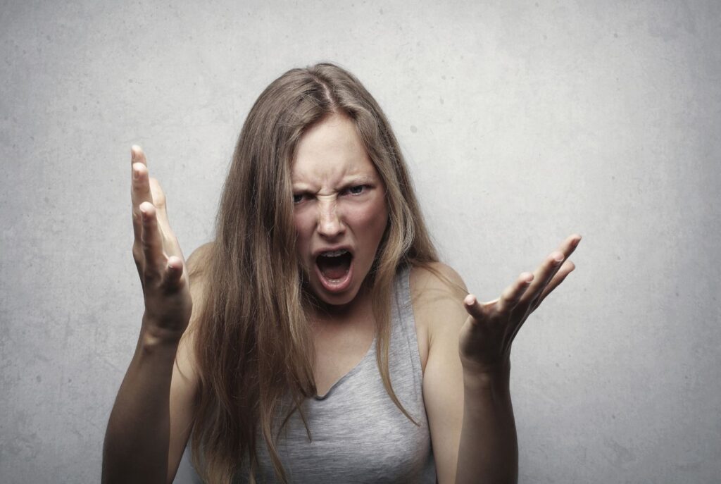 A lady expressing anger with her hands raised and a frustrated face.