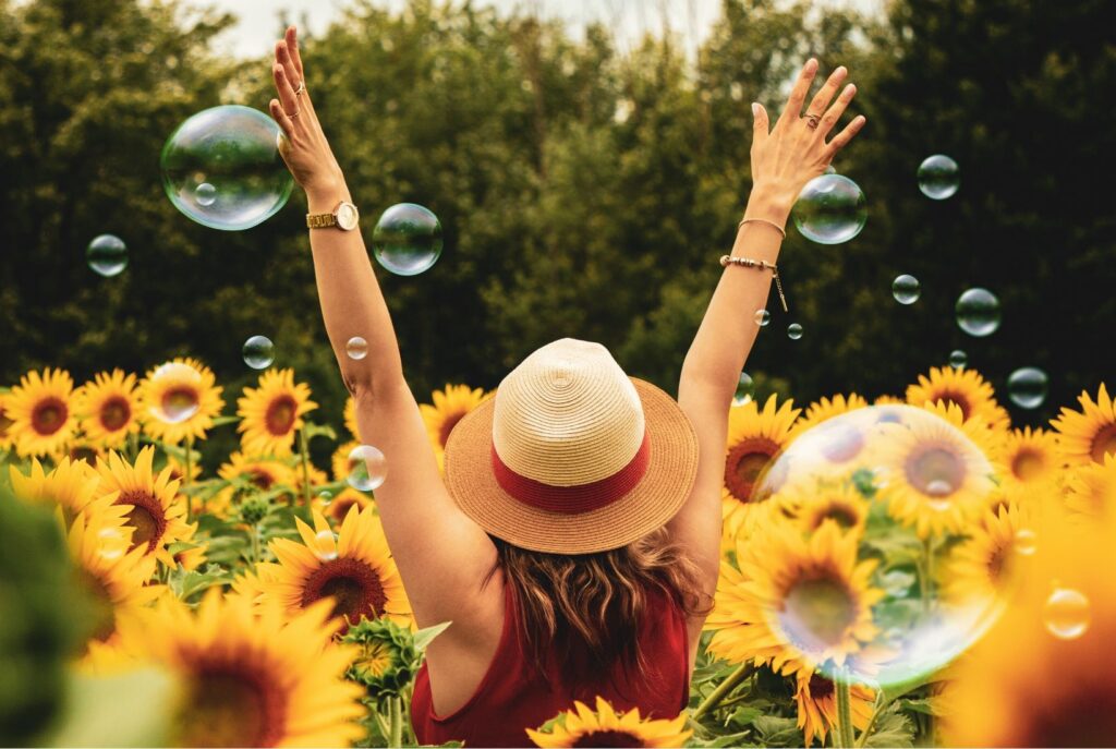 Lady in a sunflower field surrounded by bubbles. Accepting emotions.