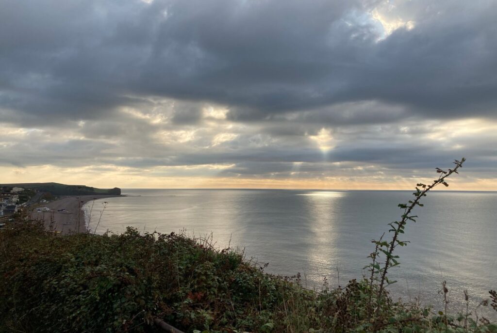 Sun setting over the sea with dark clouds.